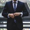 man in business suit adjusts his jacket and tie