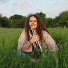 Anna Kallinikos, sitting in a field with her trumpet