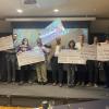 faculty, researchers and graduate students pose with giant checks