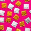 White and gold condoms on pink background