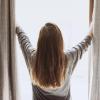 Person opening up curtains to let light into room