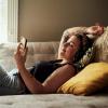 person lying on couch and scrolling on their phone