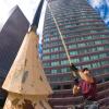 A worker is seen with a long pole, painting a flagpole in downtown Denver.
