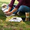 student sitting in grass working on a computer