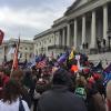 Crowd waving flags amasses in front of the U.S. Capitol building