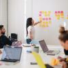 A person stands near a wall with several colorful Post-It notes. (Jason Goodman/Unsplash)