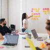 Person putting sticky notes on a wall during a meeting