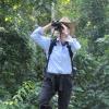 Joanna Lambert standing on tree limb and looking through binoculars.