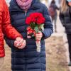 Two people, one of them carrying a bouquet of flowers, hold hands.