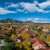 An aerial view of part of the CU Boulder campus shows colorful fall foliage, the Flatirons in the distance and a bright blue sky with light clouds.