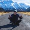 Ku Thomas sits in road in front of Aoraki Mountain in New Zealand