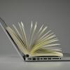 A laptop and book with its pages open. 