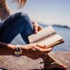 Person reads book water-side