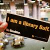 Person holding a 'I am a library Buff' bumper sticker