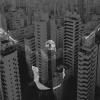 An image of a woman is superimposed in black and white over skyscrapers