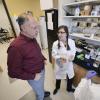 Karl Linden examines a petri dish with students in the lab