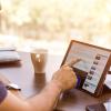 Person using tablet and drinking a cup of coffee