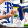 Researcher works with cyanobacteria, a green substance, in beaker