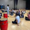 Dance students sit in a studio, listening to instructor