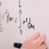 person writes equation on white board