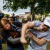 two men fighting in a public park while onlookers watch