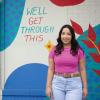 Mia Torres in front of a mural that says: We'll get through this