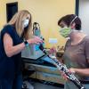 Graduate student Teyha Stockman, right, shows off her homemade bell cover made from medical mask material that helps decrease aerosol spread on her clarinet