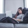 person works on laptop while sitting on couch