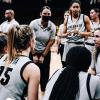 Members of the CU women's basketball team in a huddle on court.