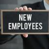 A hand holds a sign that reads "new employees"