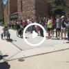Students competing in an engineering competition with a play button graphic overlay