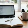 A laptop, cup of coffee and a notebook