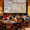 New students, families and volunteers sit at tables during Fall Welcome