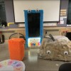 Shaggy, colorful, fun-looking instruments and game boards with googly eyes rest on a floor.