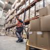 A person pulls a pallet of boxes through a warehouse