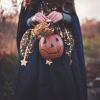 person in black Halloween costume and holding a jack-o-lantern