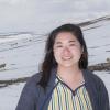 Peace Corps volunteer in front of sheep on snowy hill