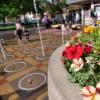 A Pearl street fountain with petuna flowers and children playing in the background.