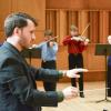 Person directs string orchestra
