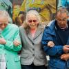 Two women and a man walk arm-in-arm down the street