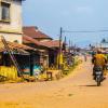 Man riding motorbike in village.