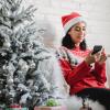 person on phone sitting next to Christmas tree