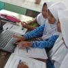 Young students work through PhET simulation on laptop
