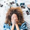 person lying on bed with hands over face
