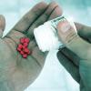 Man pouring pills out of bottle and into hand