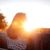 Woman standing on a footbridge at sunset