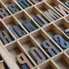 Letterpress letters are resting in a wooden box.