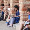 Several students sit between columns of a building studying. 