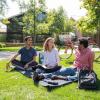 Group of students sitting on the grass at Kittredge Pond smiling