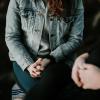 Young person sits with hands folded